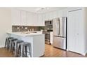 Modern kitchen with white cabinets, stainless steel appliances, and a breakfast bar at 3470 S Poplar St # 404, Denver, CO 80224