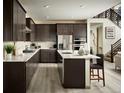 Modern kitchen featuring dark wood cabinetry, stainless steel appliances, and a white marble island at 9973 Worchester St, Commerce City, CO 80022