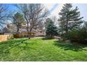 Expansive backyard with lush lawn, mature trees, and a covered patio ideal for outdoor entertaining at 13183 Spica Dr, Lone Tree, CO 80124