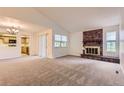 Bright living room featuring a brick fireplace and views into the kitchen at 13940 E Linvale Pl, Aurora, CO 80014