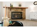 Close-up of the stone fireplace with mantel decor, brass fireplace tools, and a modern white cabinet at 3452 S Eagle St # 101, Aurora, CO 80014