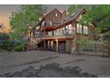 Stunning multi-level home featuring wood siding, large deck, and a stone garage, nestled in a scenic wooded landscape at 34127 Cactus Dr, Evergreen, CO 80439