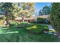 Classic brick home featuring lush, verdant landscaping, mature trees, and a well-maintained lawn at 4000 S Clermont St, Cherry Hills Village, CO 80113