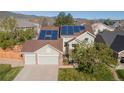 Inviting front of home with a three-car garage, solar panels, and mountain views at 9525 W Victoria Dr, Littleton, CO 80128