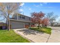Two story home with an attached two car garage, grass yard, and blue sky at 4860 S Field Way, Littleton, CO 80123