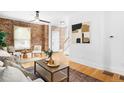 Open-concept living space with exposed brick, modern art, and hardwood flooring at 3375 W 37Th Ave, Denver, CO 80211