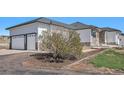 Attached three-car garage with white doors, situated next to the home's stone and siding exterior at 10071 E 142Nd Ave, Brighton, CO 80602