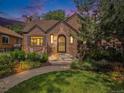 Charming brick home featuring a landscaped front yard and inviting entrance at dusk at 1423 Dahlia St, Denver, CO 80220