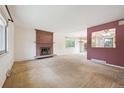 Spacious living room featuring a red brick fireplace, large window and open access to dining area at 7264 S Platte Canyon Dr, Littleton, CO 80128