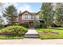Two-story Tudor-style home featuring lush landscaping, brick and white stucco exterior and a charming green roof at 1317 Birch St, Denver, CO 80220