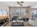 Comfortable living room with a gray sofa, white accent chair, ceiling fan, and lots of natural light at 17326 Waterhouse Cir # B, Parker, CO 80134