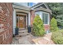 Inviting front entrance with a wood door, brick accents, and manicured landscaping at 21416 E Ottawa Cir, Aurora, CO 80016
