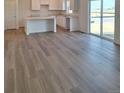 Bright, open-concept living space with wood-style flooring and a modern white kitchen at 15296 Fillmore St, Thornton, CO 80602
