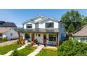 Inviting two-story house boasts a charming porch with seating and meticulously maintained landscaping in a bright, sunny setting at 2571 S Cherokee St, Denver, CO 80223