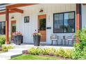 Close-up showcasing the inviting porch with stylish seating, potted flowers, and elegant exterior details at 2571 S Cherokee St, Denver, CO 80223