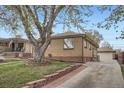 Brick home with a detached garage, featuring a paved driveway and neat landscaping on a sunny day at 4840 Depew St, Denver, CO 80212