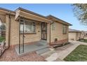 Close-up of the front entrance of a charming brick home with a decorative security door and small porch at 4840 Depew St, Denver, CO 80212