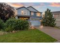 Two-story home featuring manicured front lawn, stone accents, a two-car garage and fresh blue paint at 19067 W 57Th Dr, Golden, CO 80403