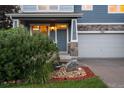 Charming exterior showcasing lush landscaping, stone accents, covered porch, and a two-car garage at 19067 W 57Th Dr, Golden, CO 80403