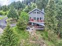 Serene aerial view of a two-story gray home nestled amidst lush greenery and trees, surrounded by a tranquil landscape at 7273 Silverhorn Dr, Evergreen, CO 80439