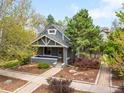 Charming gray painted duplex home with a front porch, landscaped garden, and mature trees against a sunny blue sky at 1518-1520 S Sherman St, Denver, CO 80210