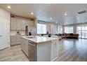 Open floor plan features a kitchen with island and a living area with large windows and a brown sectional at 2785 Black Hawk Pl, Brighton, CO 80601