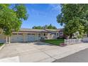 Charming home with a spacious driveway, attached garage, well-manicured lawn, and a white picket fence at 8001 W 57Th Ave, Arvada, CO 80002