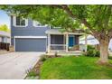 Inviting two-story home with a blue front door, covered porch, beautiful landscaping, and an attached two-car garage at 1672 Maccullen Dr, Erie, CO 80516
