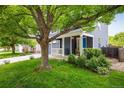 Charming front exterior featuring a blue home, lush lawn, covered porch with seating, and mature shade trees at 1672 Maccullen Dr, Erie, CO 80516