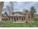 Backyard of home featuring a solarium, brick chimney, patio with outdoor dining, and a well-maintained lawn at 3633 S Ingalls St, Denver, CO 80235