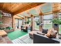 Bright sunroom featuring brick walls, wood ceilings, skylights, and comfortable seating, with a garden view at 3633 S Ingalls St, Denver, CO 80235