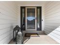Close-up of front door with storm door and side windows, complemented by a decorative lantern and 