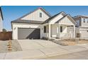 Charming single-Gathering home with a covered porch, gray two-car garage, and modern architectural details at 200 Lark Sparrow Way, Bennett, CO 80102