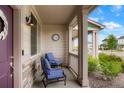 Cozy covered front porch with seating area and stone accents on support columns at 21528 E 59Th Pl, Aurora, CO 80019