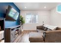 Bright living room with a gray sofa, large windows, and an entertainment center with decor at 21528 E 59Th Pl, Aurora, CO 80019