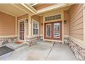 Covered porch with glass panel front door, a storm door, and stone accents at 9784 S Iris Ct, Littleton, CO 80127
