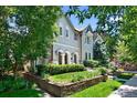 Attractive home with manicured lawn, framed flower beds, mature trees, and charming architectural design at 1164 S High St, Denver, CO 80210
