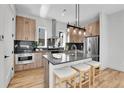 Modern kitchen featuring wood cabinetry, stainless steel appliances, and an island with seating at 5920 W 91St Ave, Westminster, CO 80031