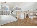 Open-concept layout with staircase, wood floors, and a modern kitchen in the background at 42958 Colonial Trl, Elizabeth, CO 80107