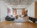 Modern living room featuring exposed brick, decorative rug, and comfortable seating under a concrete ceiling at 1449 Wynkoop St # 305, Denver, CO 80202