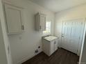 Laundry room features granite countertop, utility sink, shaker cabinets, door to outside, and wood look floors at 59440 E 56Th Ave, Strasburg, CO 80136