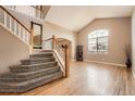 Elegant entryway featuring a staircase with wood railing, large window, and gleaming hardwood floors providing a warm welcome at 10089 Wynwood Way, Highlands Ranch, CO 80126