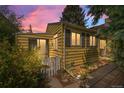 Charming yellow home featuring a white picket fence, siding, and black shuttered windows, nestled under a colorful sky at 1665 S Madison St, Denver, CO 80210