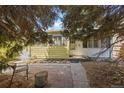 View of the front of the home with its yellow and white siding, complemented by a tree and front yard at 1665 S Madison St, Denver, CO 80210