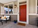 Welcoming front porch with a cozy seating area and a vibrant, red front door at 5511 Wabash St, Denver, CO 80238