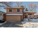 Charming two-story house with a two-car garage, complemented by landscaped snow covered greenery at 7318 W Cedar Cir, Lakewood, CO 80226