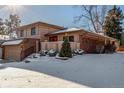 A charming two-story home has a two-car garage and a cozy, snow-covered landscaped front yard at 7318 W Cedar Cir, Lakewood, CO 80226