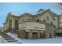 Two-story townhouse with charming balcony and front entrance, creating a welcoming and inviting curb appeal in a snow-covered setting at 4143 Da Vinci Dr, Longmont, CO 80503