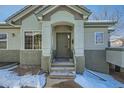 Inviting front entrance with decorative door and stone accents, creating a warm and welcoming curb appeal during winter at 4143 Da Vinci Dr, Longmont, CO 80503
