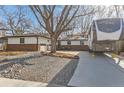 Ranch style house with mature trees, rock landscaping, and a large driveway with an RV at 1740 Shavano St, Longmont, CO 80504